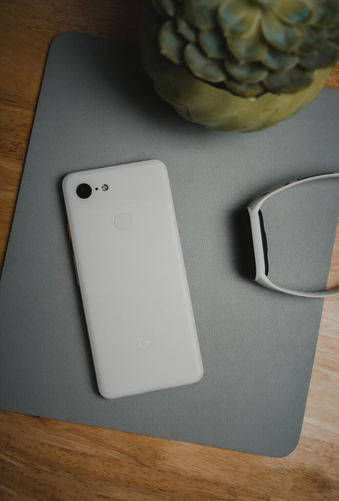 Top view of a minimalist smartphone and smartwatch on a wooden desk.